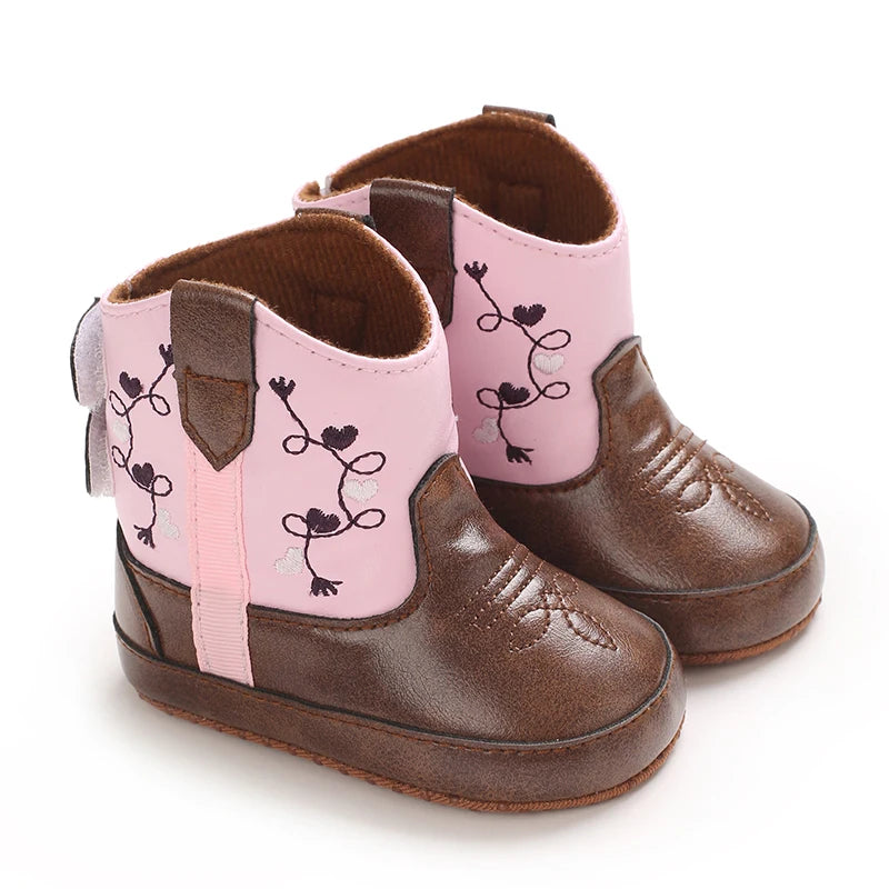 A pair of pink and brown baby Western booties with embroidered floral designs.