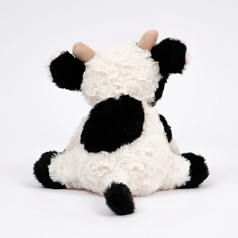 A white and black cow plush toy with floppy ears and a cute, cuddly appearance.