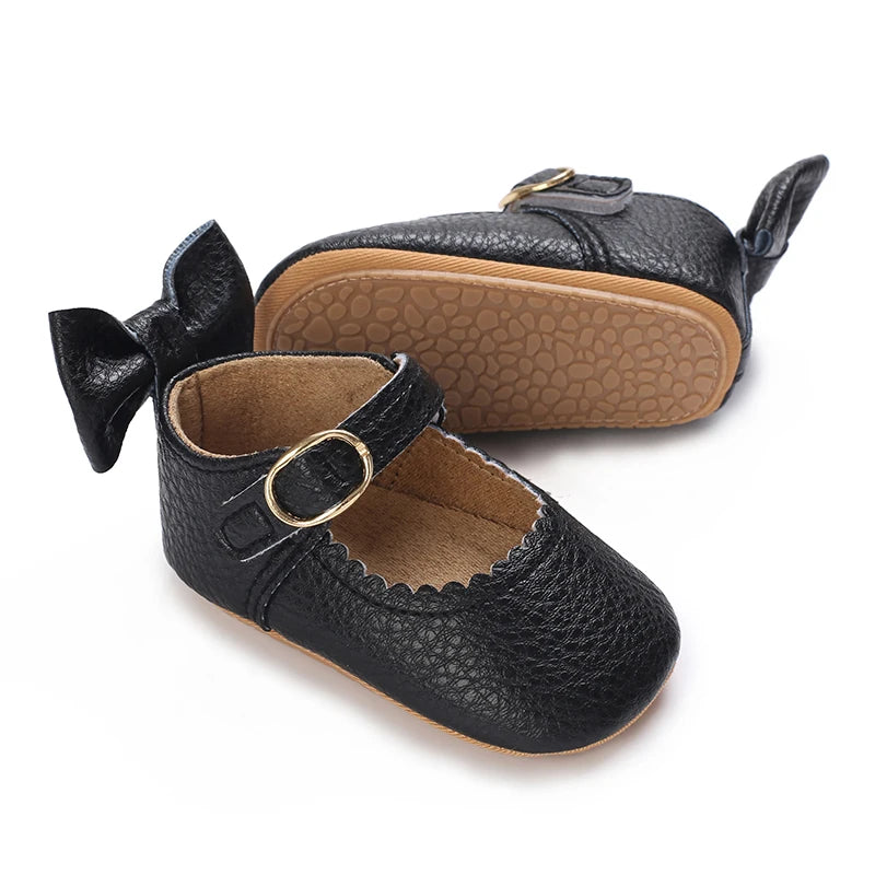 Black lace-trimmed baby girl moccasin shoes with a bow shown from the side.