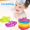 A young child is enjoying fun bathing with colorful stacking cups and floating boats in a bathtub.