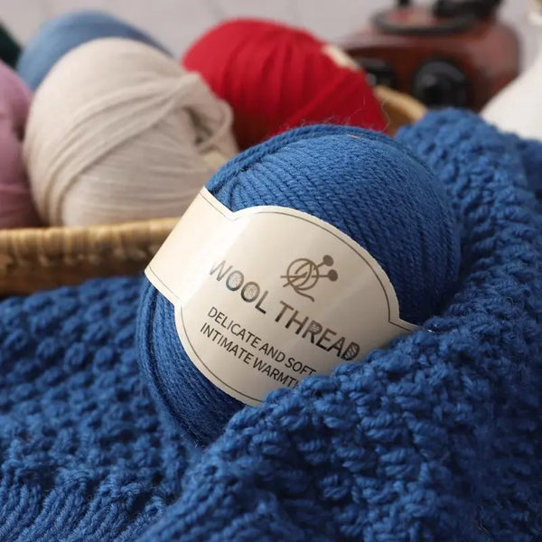 A close-up of a skein of deep blue wool thread labeled Delicate and Soft intimate warmth