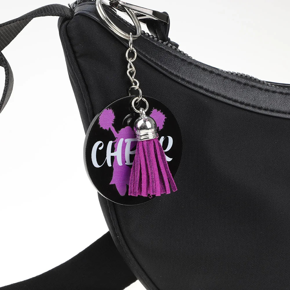 A black pouch with a silver charm featuring purple velvet tassels and the word cheer