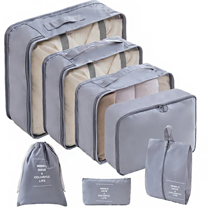 A set of gray travel packing cubes and a matching storage bag for organizing items.