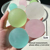 A hand holds several round, pastel-colored squishy toys, including light green, pink, and blue shades.