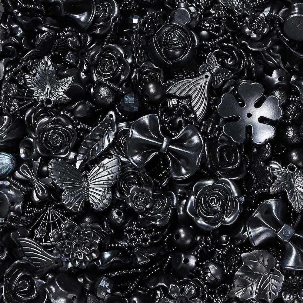 A close-up of dark, metallic, and silver butterfly-shaped acrylic beads for DIY jewelry making.