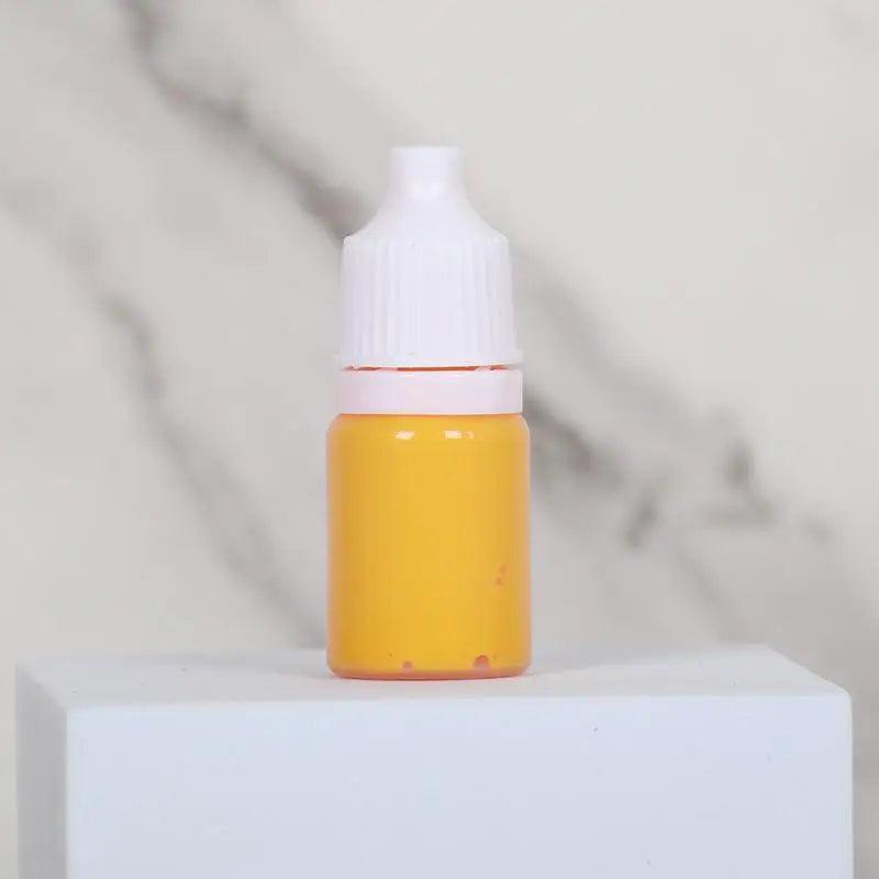 A small glass bottle of yellow liquid with a white dropper cap sitting on a white surface.