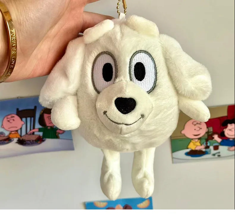 A white plush dog toy resembling a puppy is being held by a hand against a background of children's illustrations.
