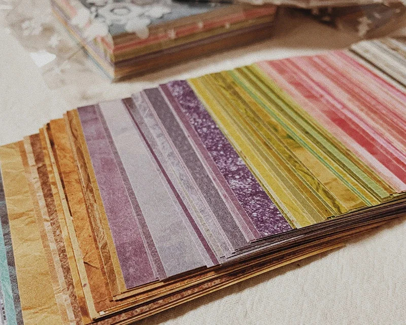 A close-up of a stack of rainbow textured paper sheets in various shades and stripes.