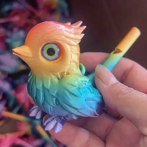 A hand holds a water activated 3D printed bird whistle toy with iridescent blue and green feathers.