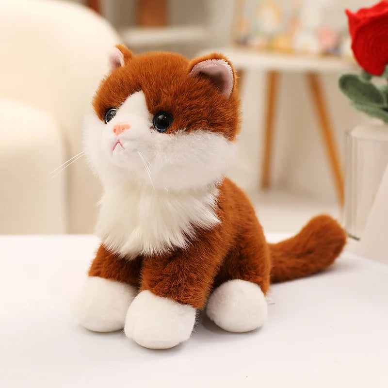 An adorable sitting kitten plush doll with orange and white fur, looking to the side.