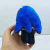 A hand is holding a bright blue plush pendant or collectible doll with black accents.