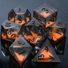 A collection of seven polyhedral liquid core resin dice resting on a dark surface.
