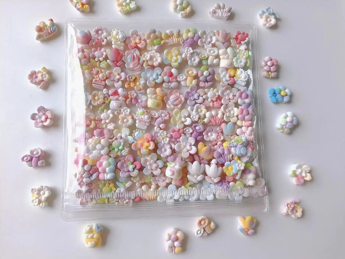 A clear plastic container filled with pink and purple floral squishy stress relief fidget toys scattered on a white surface.