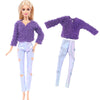 A fashion doll outfit set featuring a purple fuzzy sweater and light blue sparkly pants.