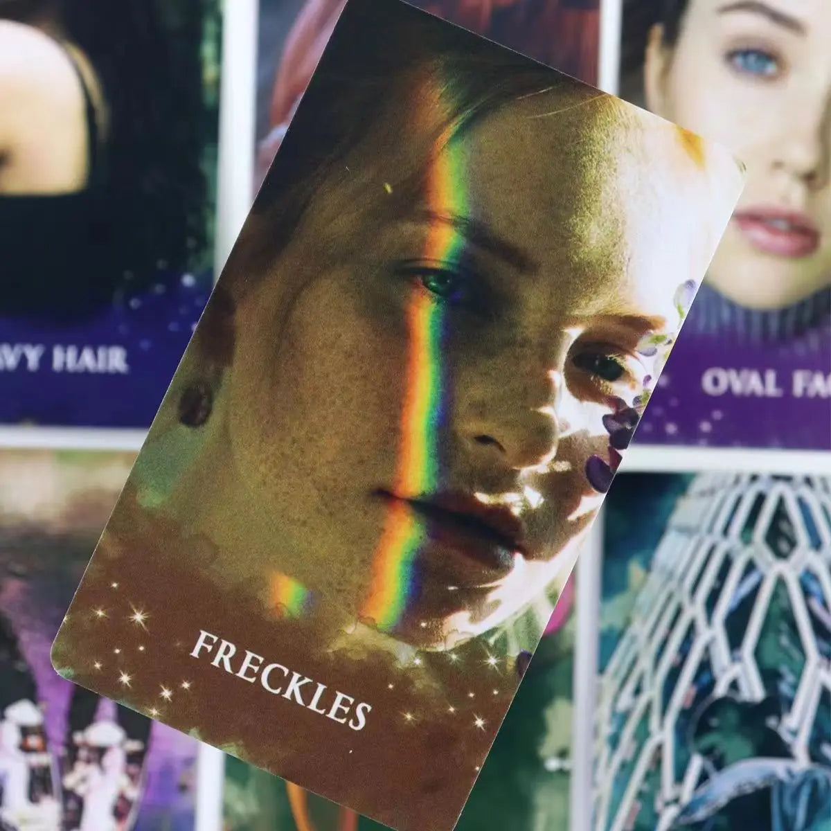 A close-up of a card from the Twin Flame Love Oracle Deck featuring a woman's face with a rainbow light effect and freckles.