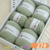 A box containing six balls of light green merino wool yarn with brown labels and a product number tag.