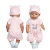 A baby doll wearing a pink outfit and a matching pink hat with a cat print shirt.