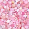 A close-up of a vibrant mix of pink and iridescent glass beads for DIY jewelry making