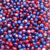A close-up view of small, round glass crackle beads in shades of red, blue, and purple.
