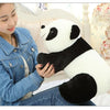 A woman is holding a white and black panda plush pillow in a light-colored room.