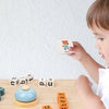 A child is playing with a Montessori wooden word spelling game featuring letters and a bear card on a wooden table.