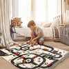 A boy plays with a kids city road map play mat featuring various toy cars indoors.