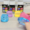 Une main tient une balle de massage rose translucide à côté de divers jouets squishy emballés.