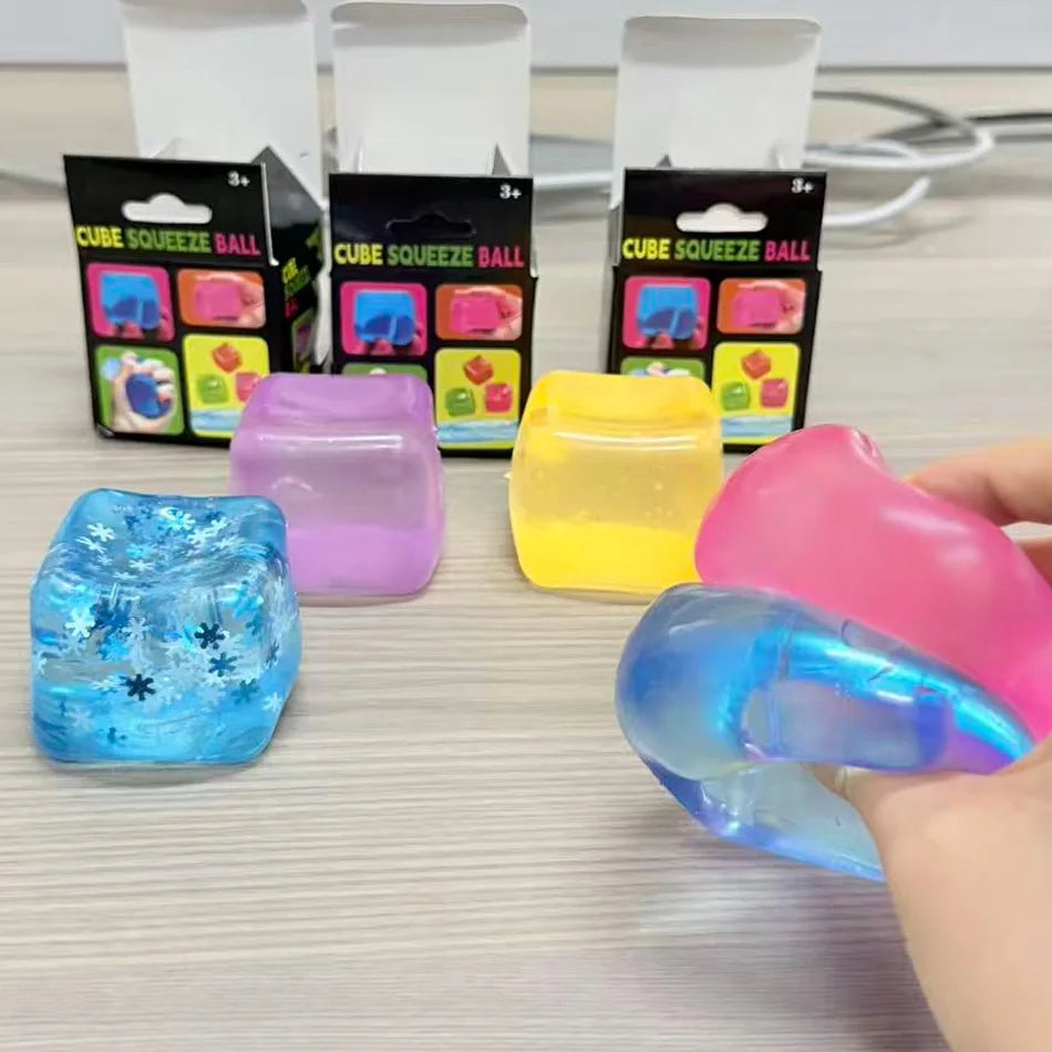 Une main tient une balle de massage rose translucide à côté de divers jouets squishy emballés.