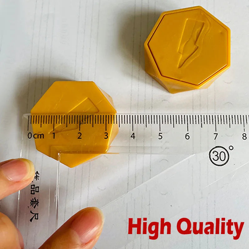 A yellow magnetic strategy board game piece shaped like a hexagon, shown next to a ruler and a hand.