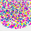 A pile of colorful polymer clay star and heart sprinkles in various shades of pink, purple, blue, yellow, and white.