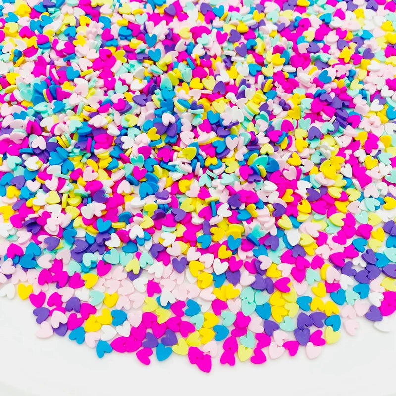 A pile of colorful polymer clay star and heart sprinkles in various shades of pink, purple, blue, yellow, and white.
