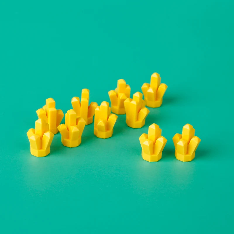 A collection of yellow building blocks arranged in a line on a teal surface.