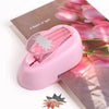 A pink lever action embosser tool rests on a sheet of paper with pink tulips.