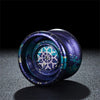 Gros plan d'un yoyo bleu foncé avec des motifs argentés et turquoise, posé sur une surface sombre.