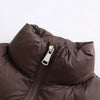 A close-up of a dark brown padded down vest with a silver zipper on the chest.