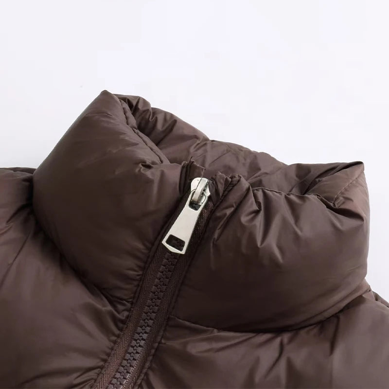 A close-up of a dark brown padded down vest with a silver zipper on the chest.