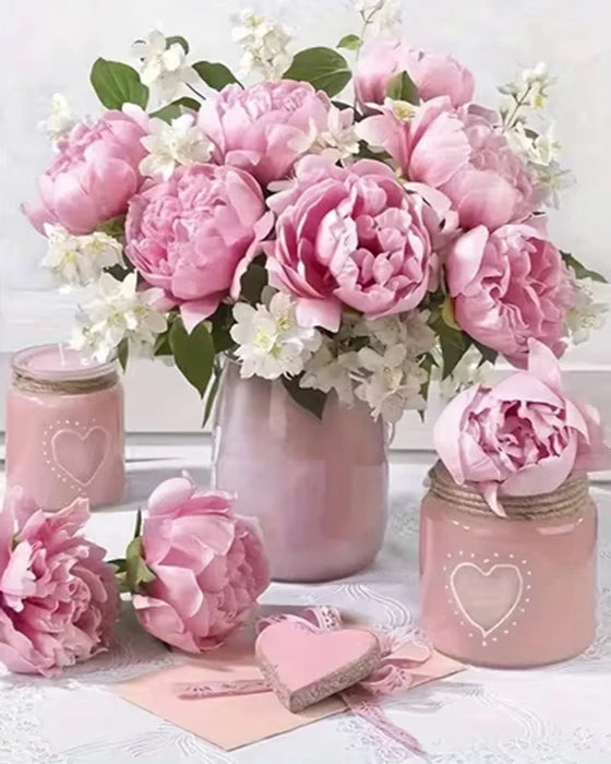 A bouquet of pink and white peonies and roses in a vase with paint by number kits nearby