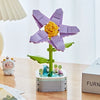 A purple rose flower building block set with a yellow center and green leaves sits on a wooden table.