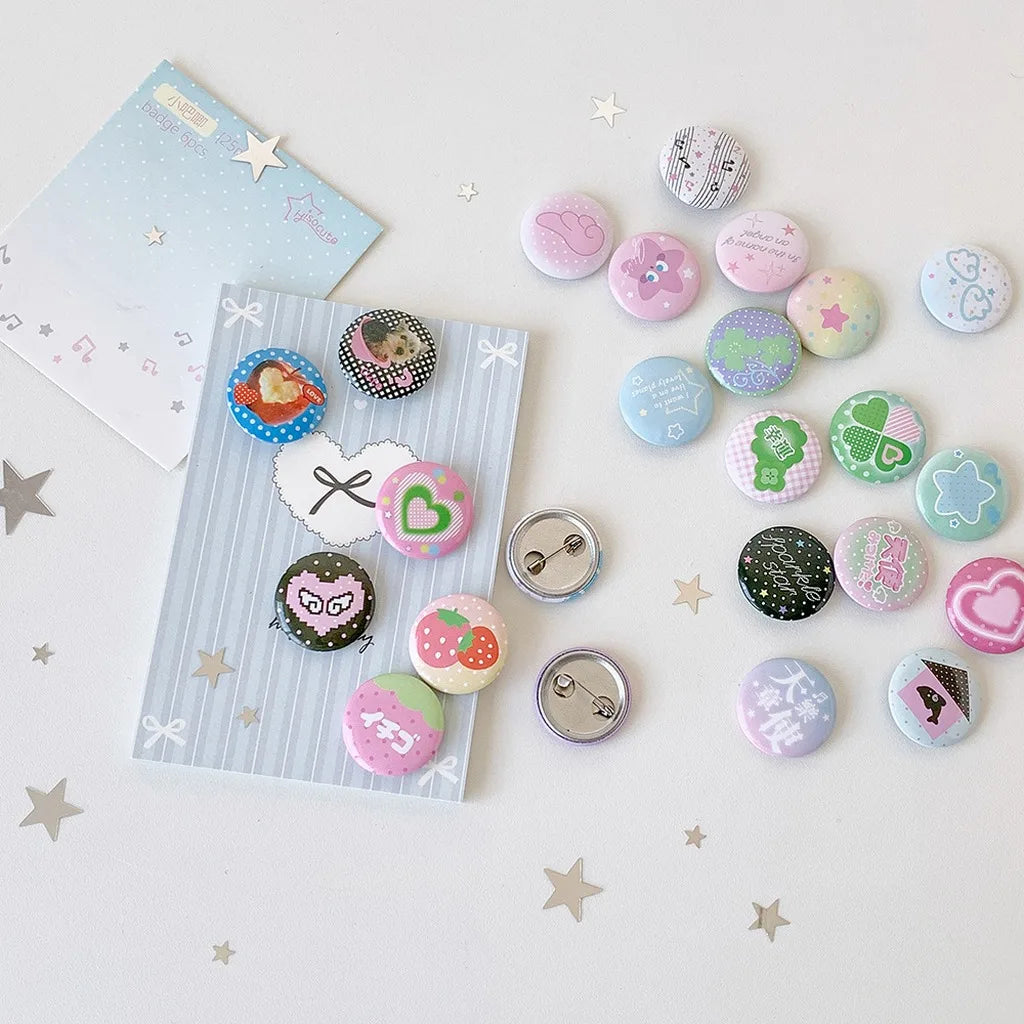 A collection of colorful kawaii mini pin badges scattered on a white surface with star confetti.