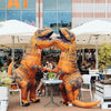 An inflatable orange T-Rex costume for adults standing in an outdoor market setting.