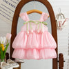 A pink tulle dress for a baby girl with ruffled sleeves and a green ribbon detail displayed on a wooden hanger.