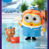A POP MART Minions collectible figure with orange hair and goggles wearing a blue outfit standing next to a small brown bear 