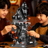 Two young boys build a detailed spooky Halloween castle structure using gray and black building blocks on a wooden table.