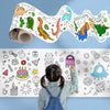 A child is drawing on a large roll of colorful dinosaur and nature-themed illustrations.
