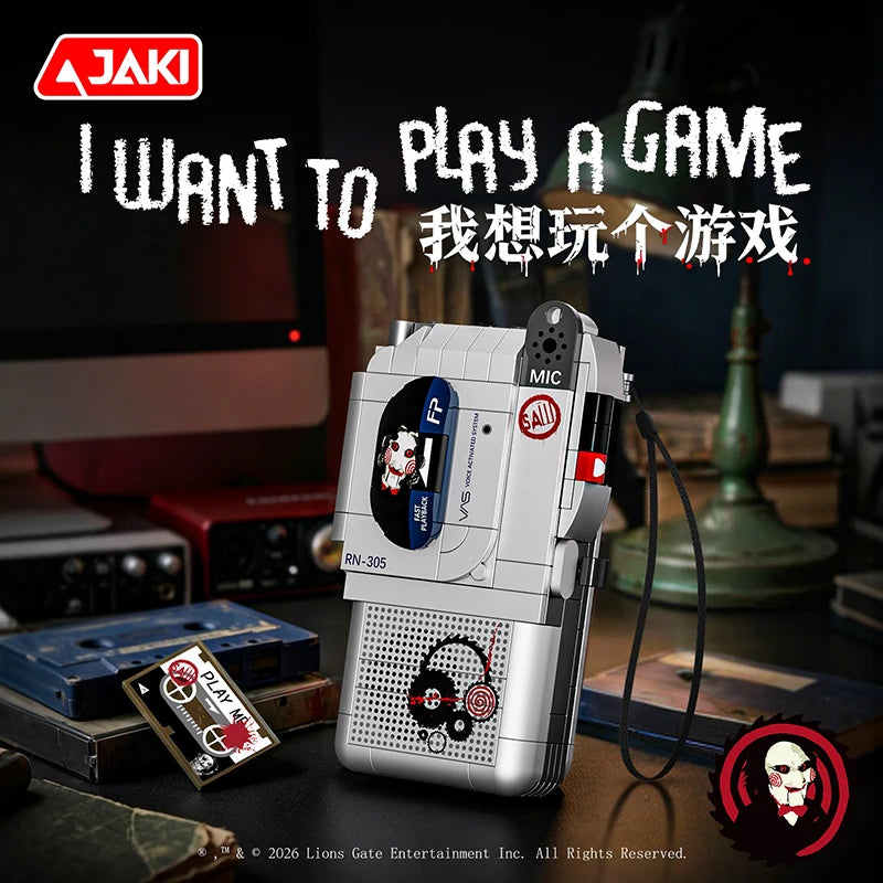 A white JAKI horror movie puppet model building set with a voice recorder displayed on a dark surface.