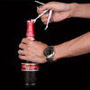 A hand is using a silver tool to remove the cap from a Budweiser bottle.