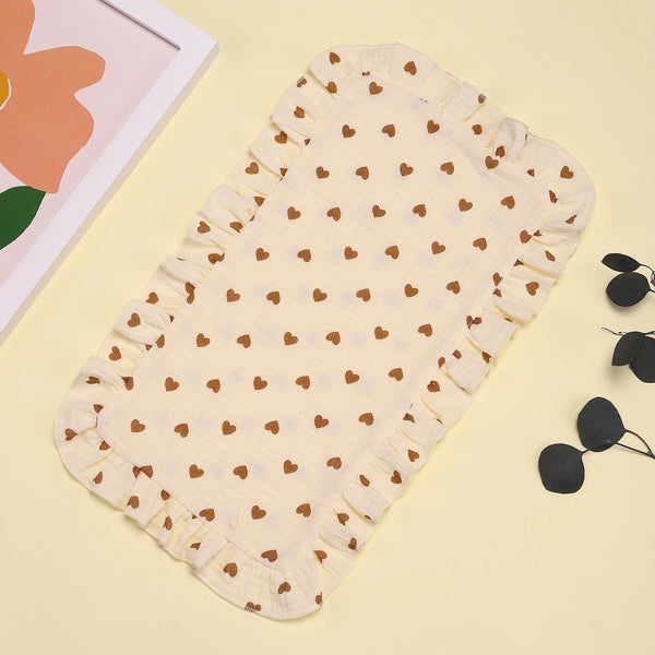 A beige muslin ruffle burp cloth set with small brown hearts, displayed on a light yellow background.