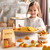 A young girl smiles while playing with a simulated making bread game set featuring various baked goods.