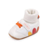 White baby booties with a ribbed cuff and anti-slip sole featuring colorful dots.