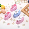 Three pink and blue lever action embossers for scrapbooking and card making placed on a white surface with floral stickers.